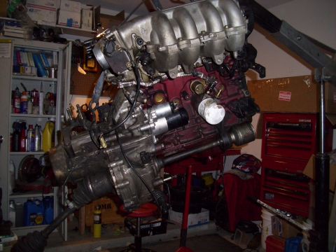 1995 Ford Probe - An engine and transmission assembly is suspended in a workshop, ready for installation or repair.