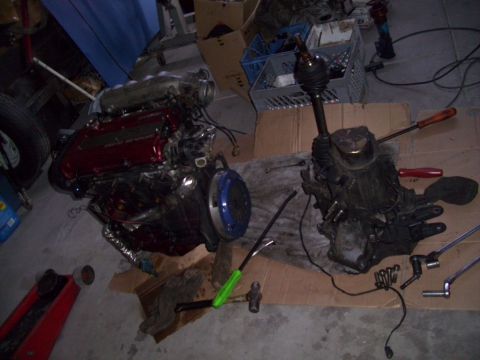 1995 Ford Probe - Engine and transmission components are disassembled and placed on the floor with various tools.