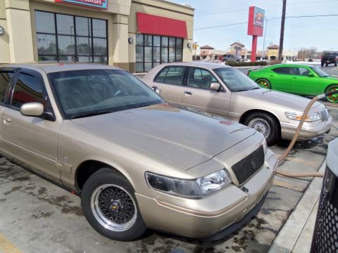 2000 Mercury Grand Marquis - Three cars are lined up at a car wash, with a gold Mercury Grand Marquis in the foreground.
