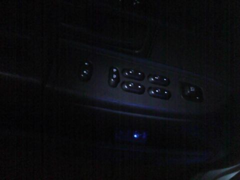 2003 Ford Crown Victoria - Illuminated window controls are visible on the dark interior door panel of a car.