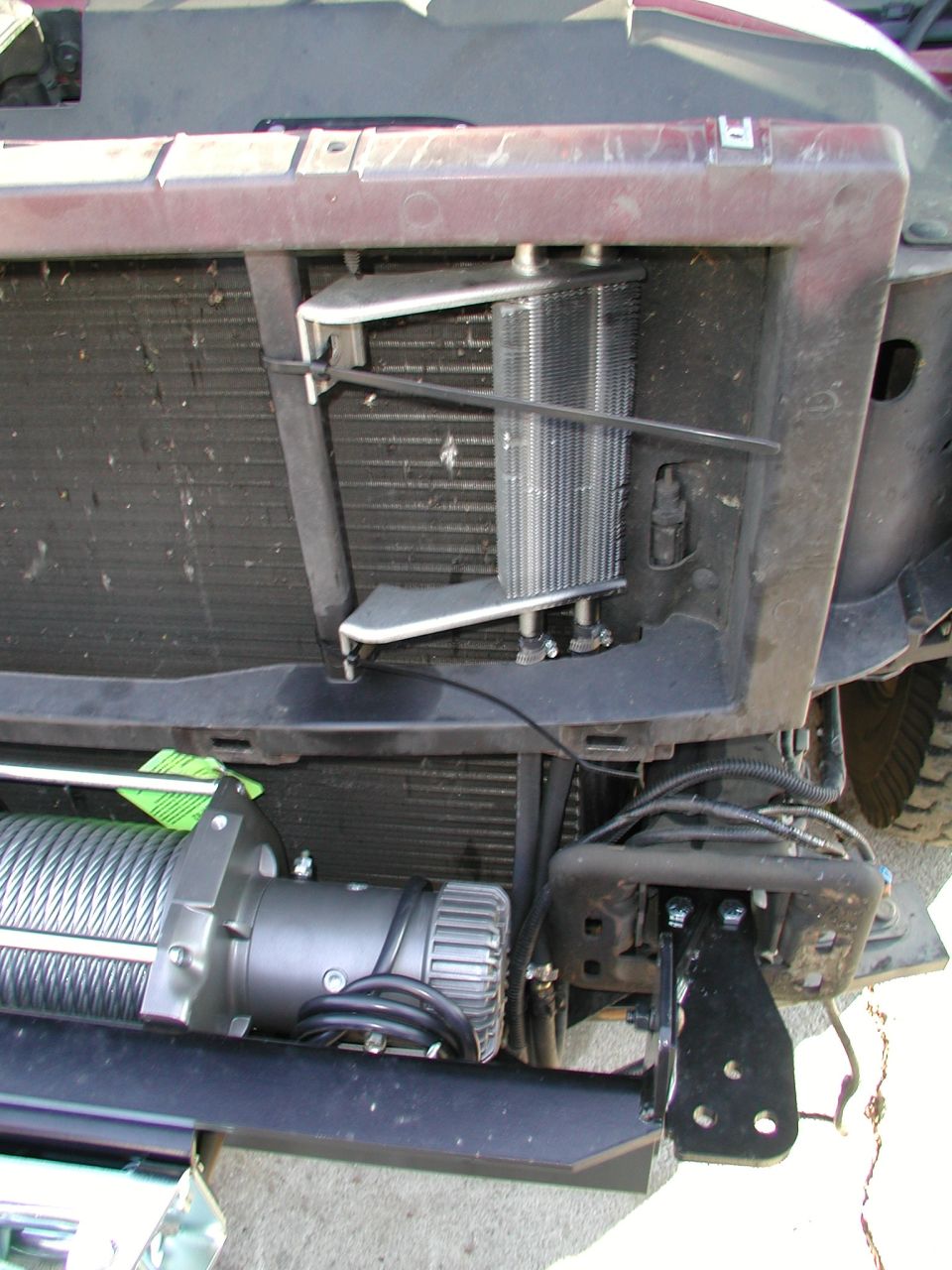 Relocating power steering cooler to make room for winch.