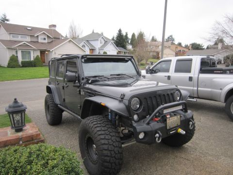 2008 Jeep Wrangler - A modified black Jeep Wrangler is parked in a driveway next to a silver pickup truck.