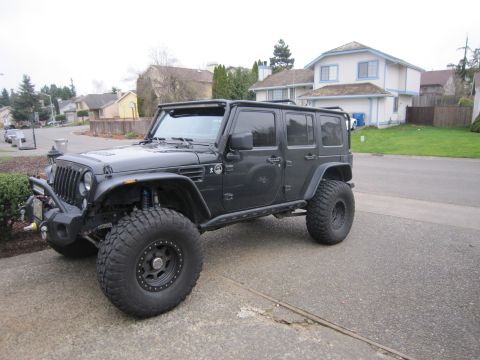 2008 Jeep Wrangler - A modified black Jeep Wrangler is parked in a suburban driveway, its off-road capabilities.