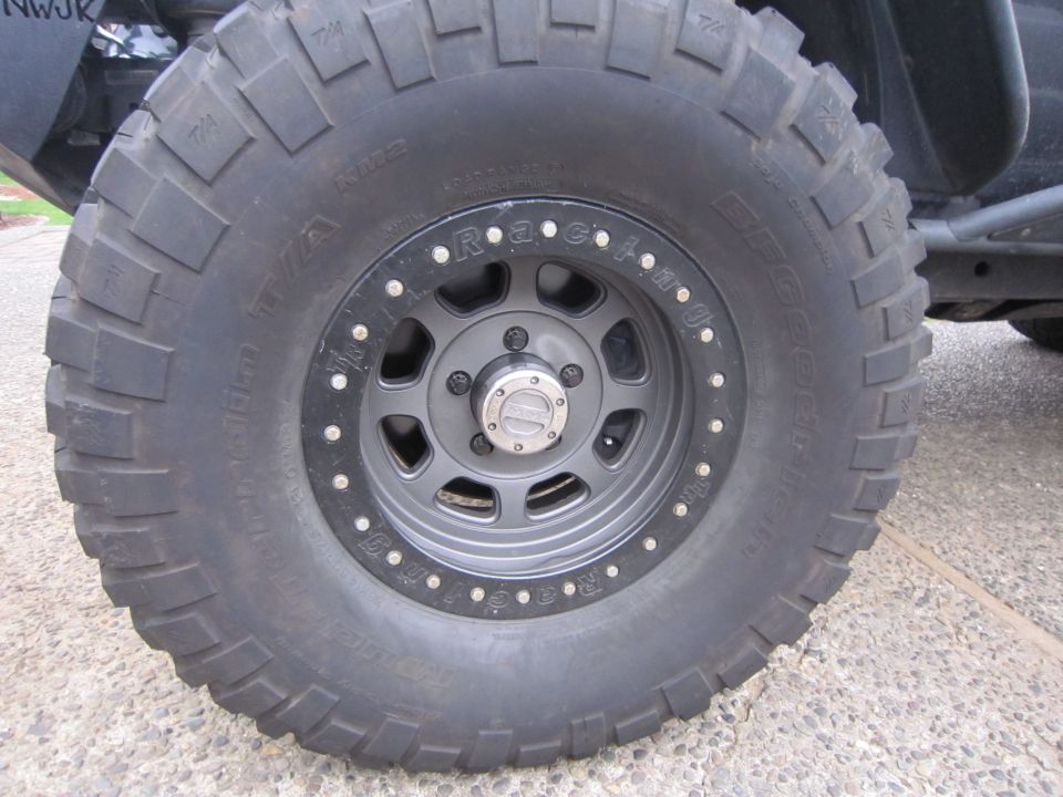 Black BFGoodrich All-Terrain T/A tire on a gray beadlock wheel, part of a Jeep Wrangler