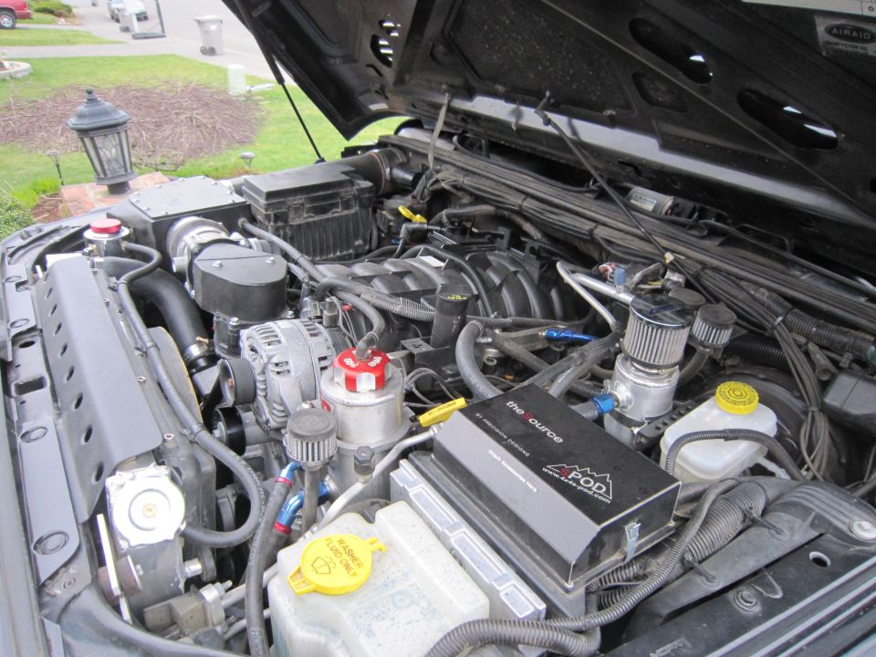 2007 Jeep Wrangler engine bay with aftermarket supercharger and air intake. "the source POD" is visible on a black box