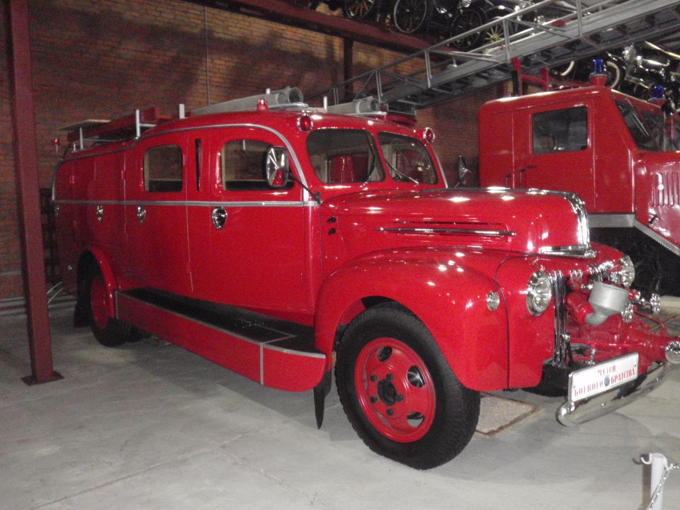 1940s red fire truck with chrome grille and headlights, parked next to another red truck