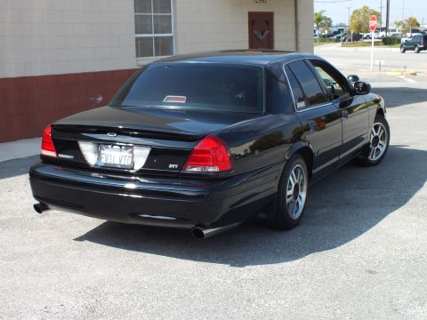 2003 Ford Crown Victoria - Rear of a black full-size sedan showing an SVT trunk badge and dual exhaust outlets.