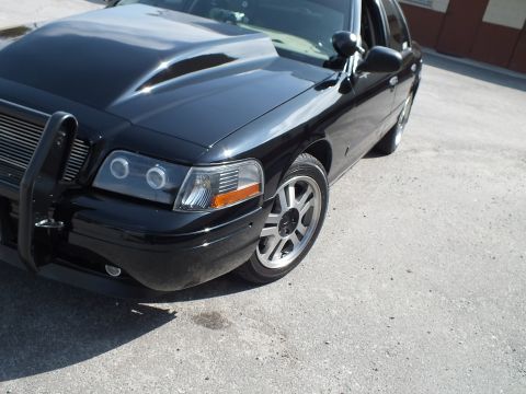 2003 Ford Crown Victoria - Front fender of a black Crown Victoria-style sedan with projector halo lamps and push bumper