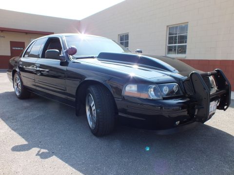 2003 Ford Crown Victoria - Black sedan three-quarter front with brush guard and alloy wheels parked in sunlight