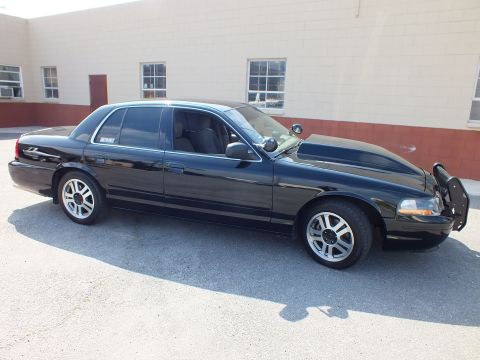 2003 Ford Crown Victoria - Full side view of a black sedan with brush guard, alloy wheels and a decal in the rear glass