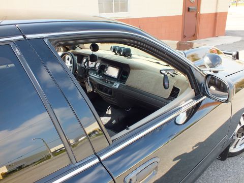 2003 Ford Crown Victoria - Looking into a black sedan's cabin: tan dashboard, navigation screen and white gauges