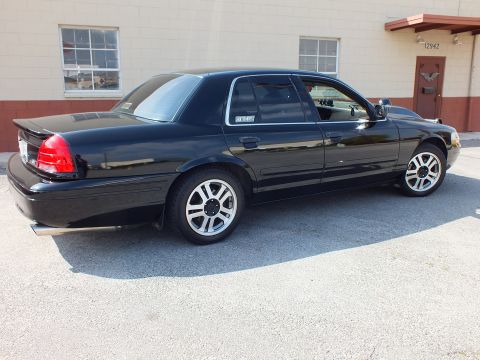 2003 Ford Crown Victoria - Rear three-quarter of a black sedan showing taillights, trunk and alloy wheels on pavement