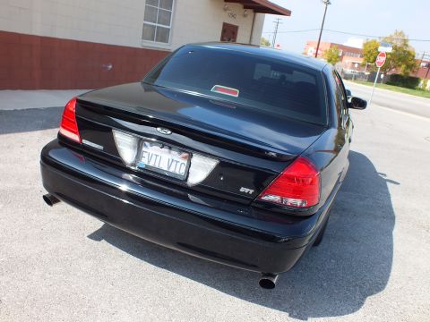 2003 Ford Crown Victoria - Straight-on rear of a black Ford sedan showing twin exhaust tips and EVIL VIC plate