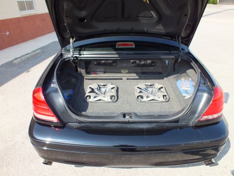 2003 Ford Crown Victoria - Black sedan trunk audio build: two chrome subwoofers and an amp mounted in carpeted box