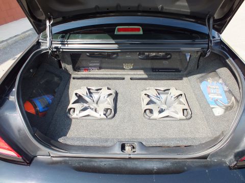 2003 Ford Crown Victoria - Carpeted trunk enclosure holding two chrome subwoofers, an amp and a spare battery