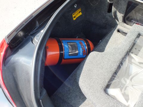 2003 Ford Crown Victoria - Orange nitrous-style bottle strapped into the carpeted trunk of a sedan