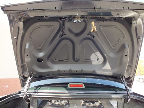 2003 Ford Crown Victoria - Open trunk lid interior with ribbed steel bracing above a carpeted cargo area and chrome trim bar