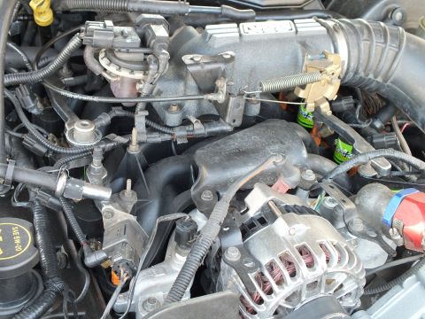 2003 Ford Crown Victoria - Detail of intake manifold, ignition coils and alternator with throttle spring and braided line