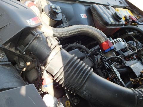 2003 Ford Crown Victoria - Ribbed air intake duct and braided line crossing the engine above the alternator