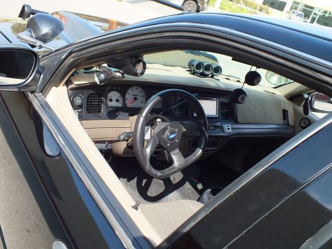 2003 Ford Crown Victoria - Driver area through open door showing aftermarket wheel, A-pillar gauge and triple dash gauge pod