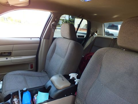2003 Ford Crown Victoria - Beige cloth front buckets with center console and rear bench seen through the cabin