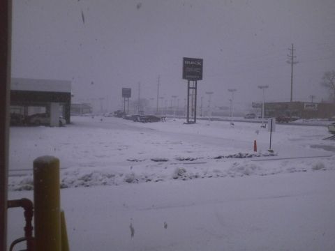 2003 Ford Crown Victoria - A snowy scene at a car dealership, with multiple vehicles visible in the lot.