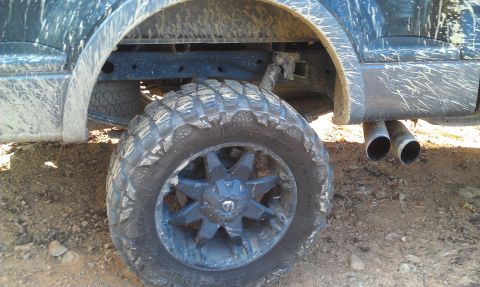 1993 Ford Bronco - A close-up view of a muddy truck's rear wheel and dual exhaust pipes, suggesting off-road use.