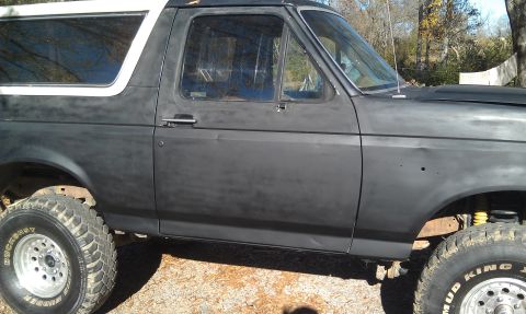 1993 Ford Bronco - Side view of a 1993 Ford Bronco with a dark primer finish and lifted suspension.