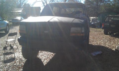 1993 Ford Bronco - Front view of a 1993 Ford Bronco parked outdoors with other vehicles visible.