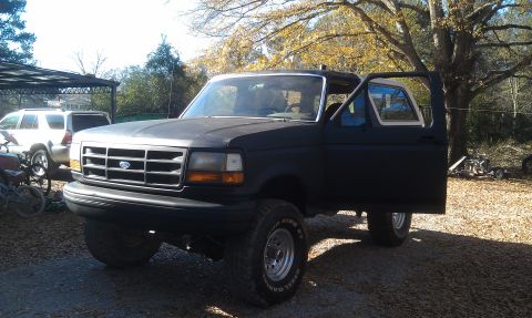 1993 Ford Bronco - A black Ford Bronco is parked outside with its driver's door ajar.