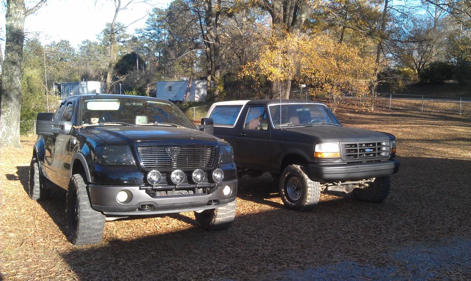 1993 Ford Bronco parked next to a newer model Ford F-150 pickup truck