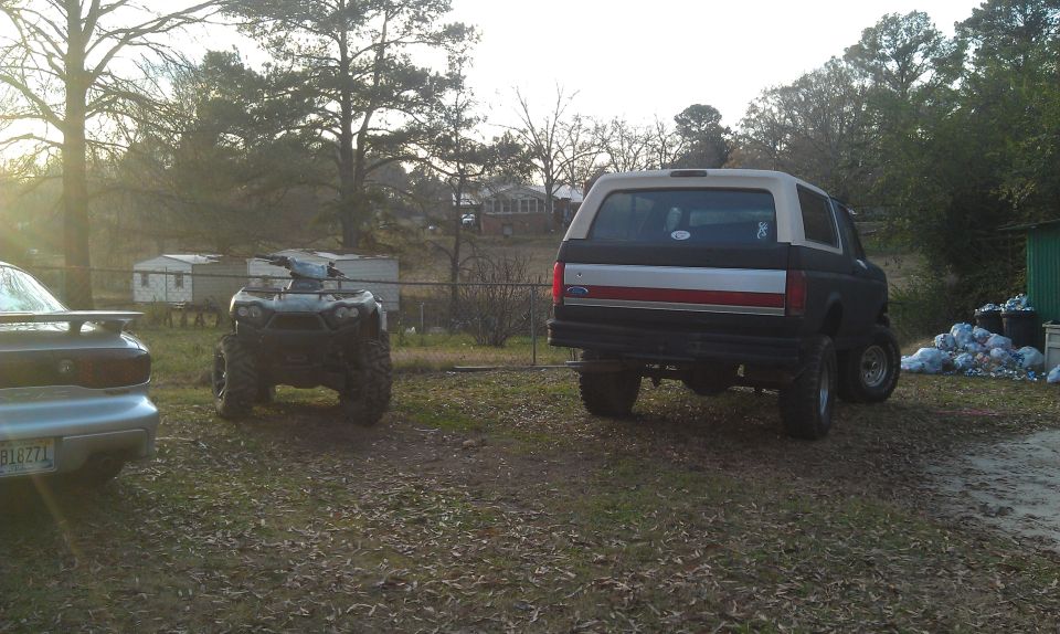 Rear view of lifted Ford Bronco and an ATV parked outside