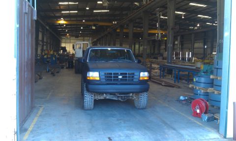 1993 Ford Bronco - Dark blue Ford F-Series truck parked indoors, likely a workshop or storage facility.