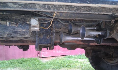 1993 Ford Bronco - Close-up view of air horns and wiring attached to the underside of a vehicle.
