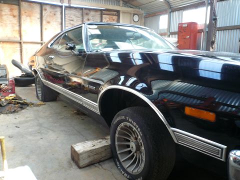 1975 Ford Ranchero - A black 1975 Ford Ranchero sits in a garage, showing off its distinctive body style and chrome accents.