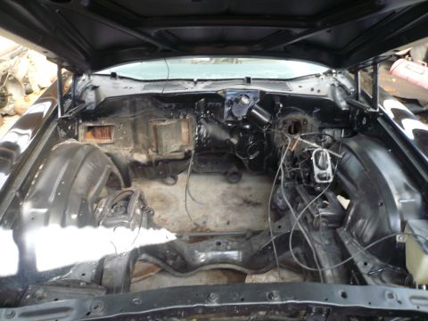 1975 Ford Ranchero - The engine bay is mostly empty, revealing the car's chassis and some components. The hood is open.