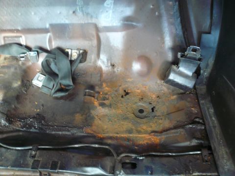 1975 Ford Ranchero - The floor of the vehicle shows significant rust and damage, with seatbelt anchors visible.