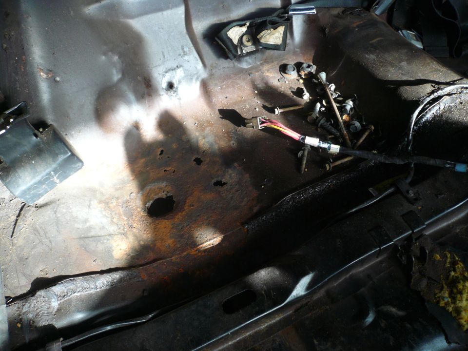 Rusted interior floor pan with wiring harness and bolts