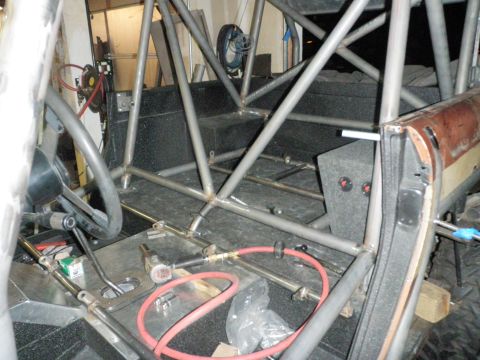 1961 International Scout 800 - The interior of a modified vehicle shows extensive roll cage construction and various tools on the floor.