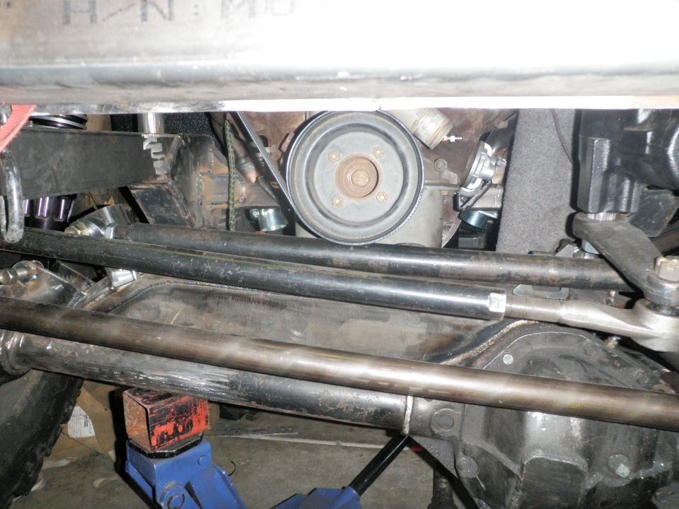 Close-up of engine pulley, belt, and steering linkage components