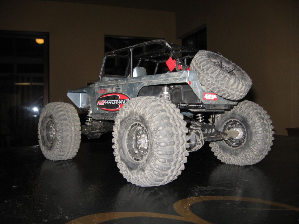 Gray remote control rock crawler with large tires and a spare tire mounted on the back