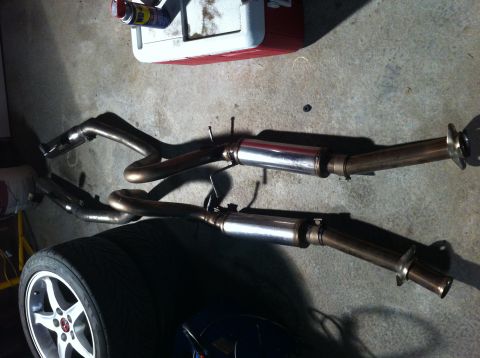 1995 Ford Mustang - Aftermarket exhaust system components are shown on the ground, possibly for a car.