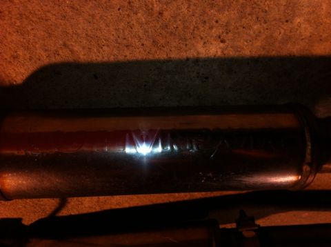 1995 Ford Mustang - The exhaust muffler shows etched text, possibly a brand name, under a bright light.