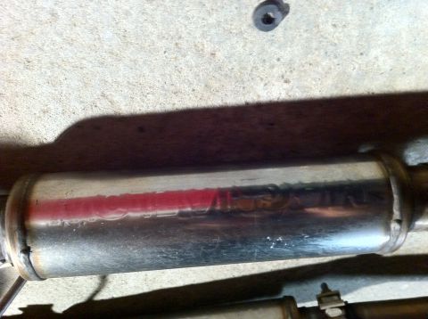 1995 Ford Mustang - A close-up view of a chrome exhaust muffler, showing red lettering and a reflection.