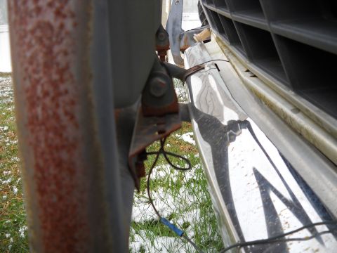 1993 Ford F-150 - A close-up shot shows a rusty bracket attached to the front of a truck, with a chrome bumper visible.