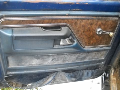 1993 Ford F-150 - Close-up of a worn car door panel, showing wood grain accents and a chrome window crank.