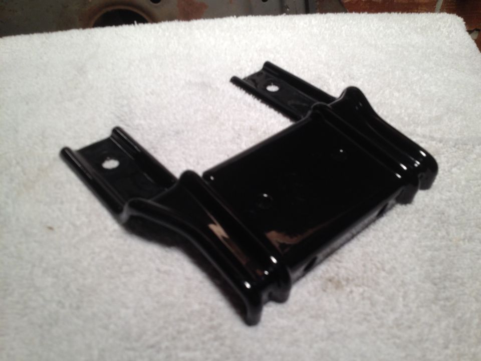 Black metal bracket with two mounting holes, resting on a white towel