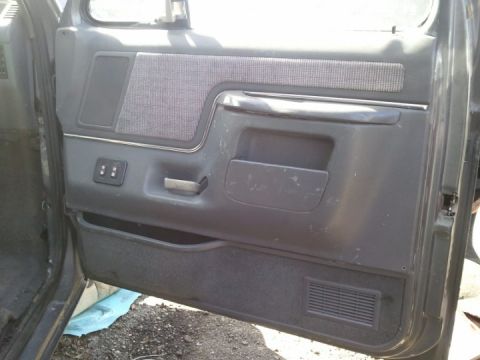 1994 Ford Bronco - Interior of a gray car door panel, showing fabric inserts and a storage compartment.