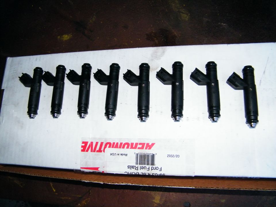 Eight black fuel injectors laid out on a white box labeled 'Ford Fuel Rails'