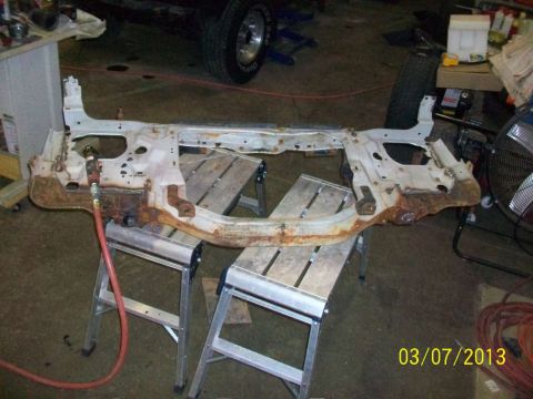 1999 Isuzu Vehicross - A heavily rusted vehicle subframe is supported by sawhorses in a workshop setting.